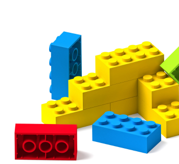 A group of colorful toy building bricks, including yellow, blue, red, and green pieces, stacked and scattered on a white background.