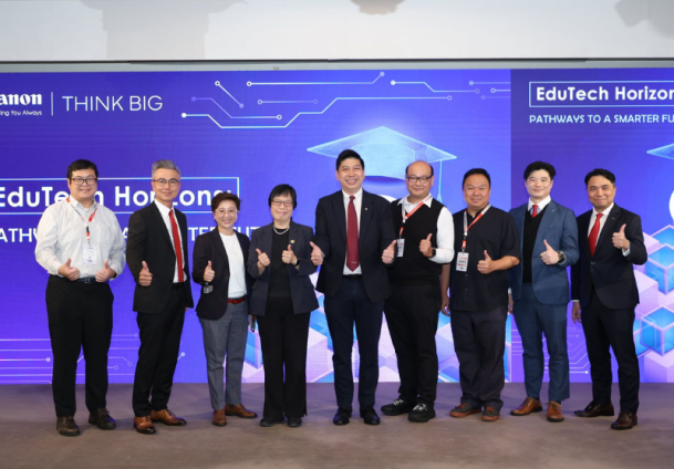 Nine people in professional attire stand in a row on stage, smiling and giving thumbs up, in front of a blue event backdrop with the “Canon” logo and the event name, ThinkBIG “EduTech Horizons: Pathways to a Smarter Future" with technology-themed graphics.